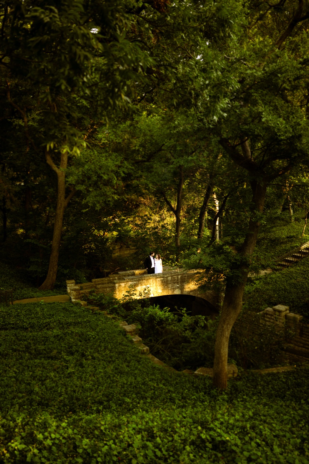 Couple on a stone bridge lit by golden light in a Dallas park