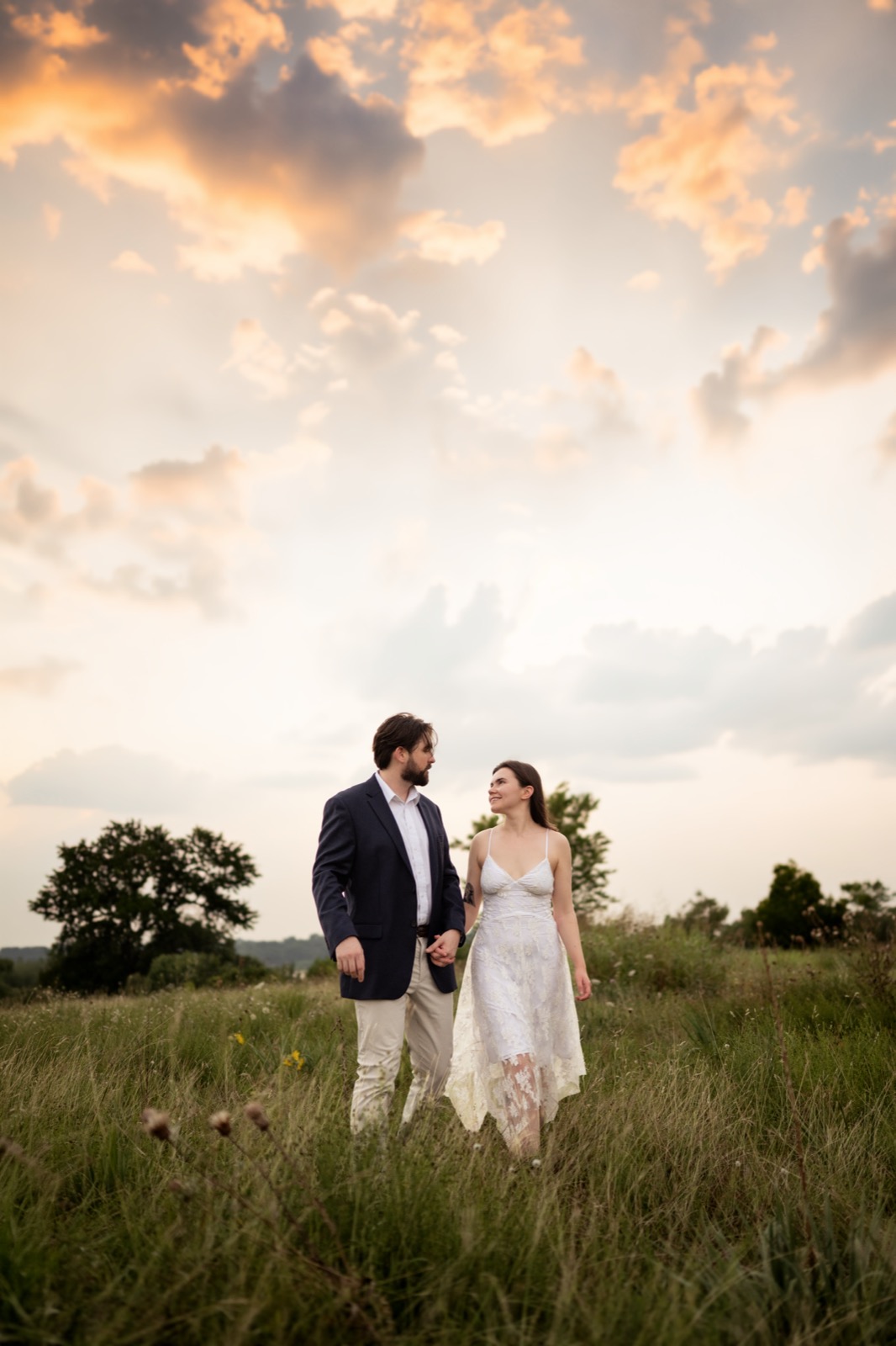 Engaged couple in a DFW field under a dramatic sunset sky